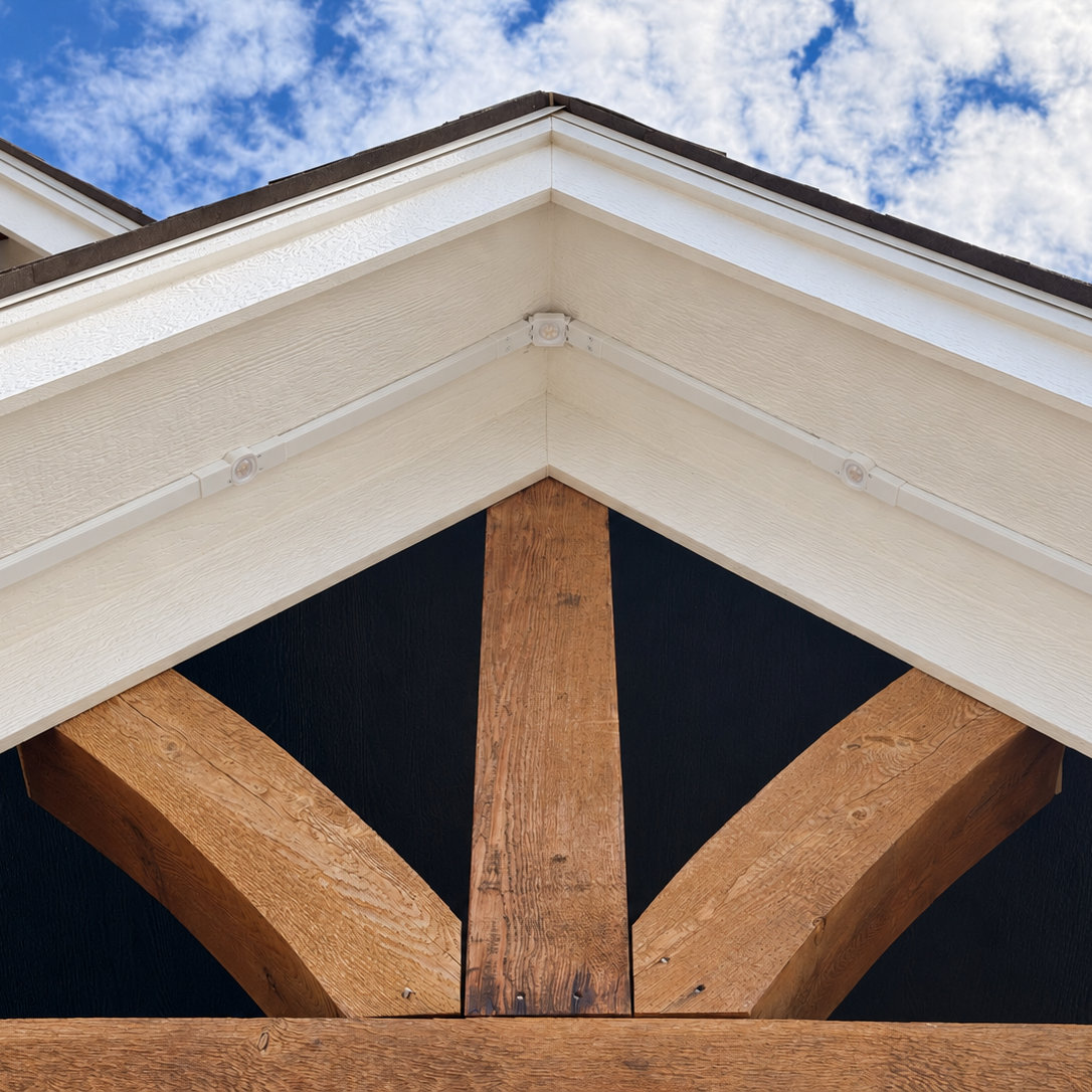 Exterior view of a white Govee Pro Channel Fit Peak Hinge connecting permanent outdoor light channels at the roof gable.