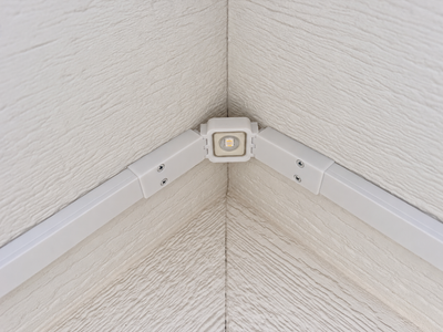 White Govee non-Pro gable bracket installed under a roof peak with a permanent outdoor LED light and wire channels.