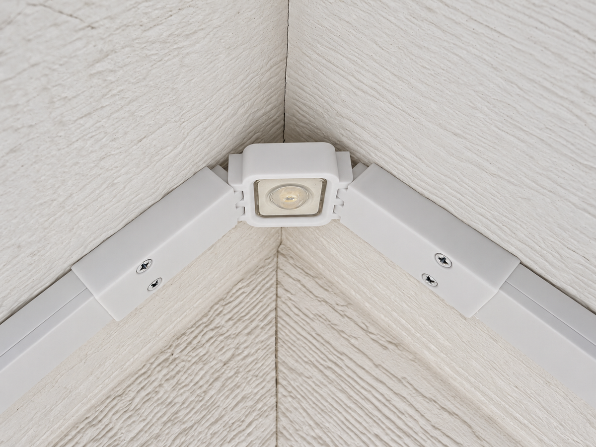 Close-up of a white Govee Lite roof peak bracket holding an LED light between channels on a textured soffit.