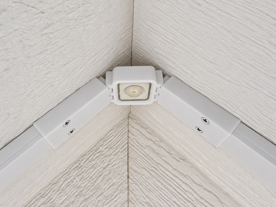 Close-up of a white Govee Lite roof peak bracket holding an LED light between channels on a textured soffit.