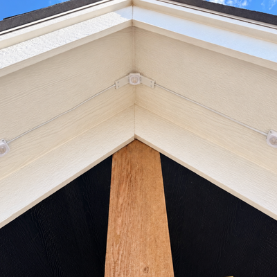 White Pro Slim Peak Hinge mounted at an exterior roof peak on cream soffit.