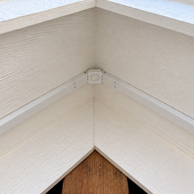 White Govee Pro Channel Fit Peak Hinge installed under a house gable, connecting light channels at the roof peak.