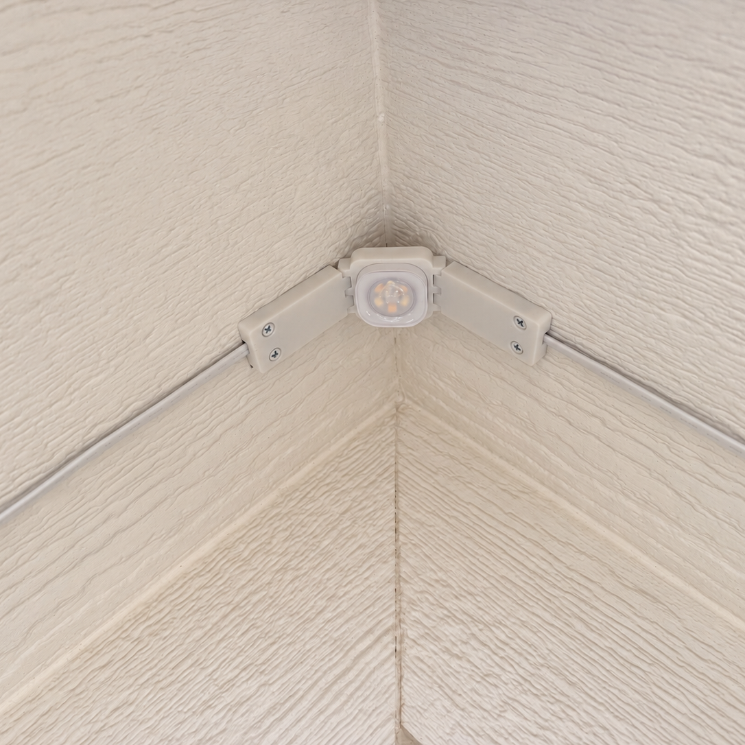 White Pro Slim Peak Hinge installed at a roof peak on cream soffit with exposed wiring.