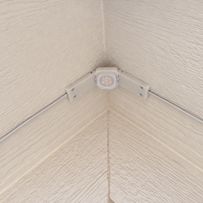 White Pro Slim Peak Hinge installed at a roof peak on cream soffit with exposed wiring.